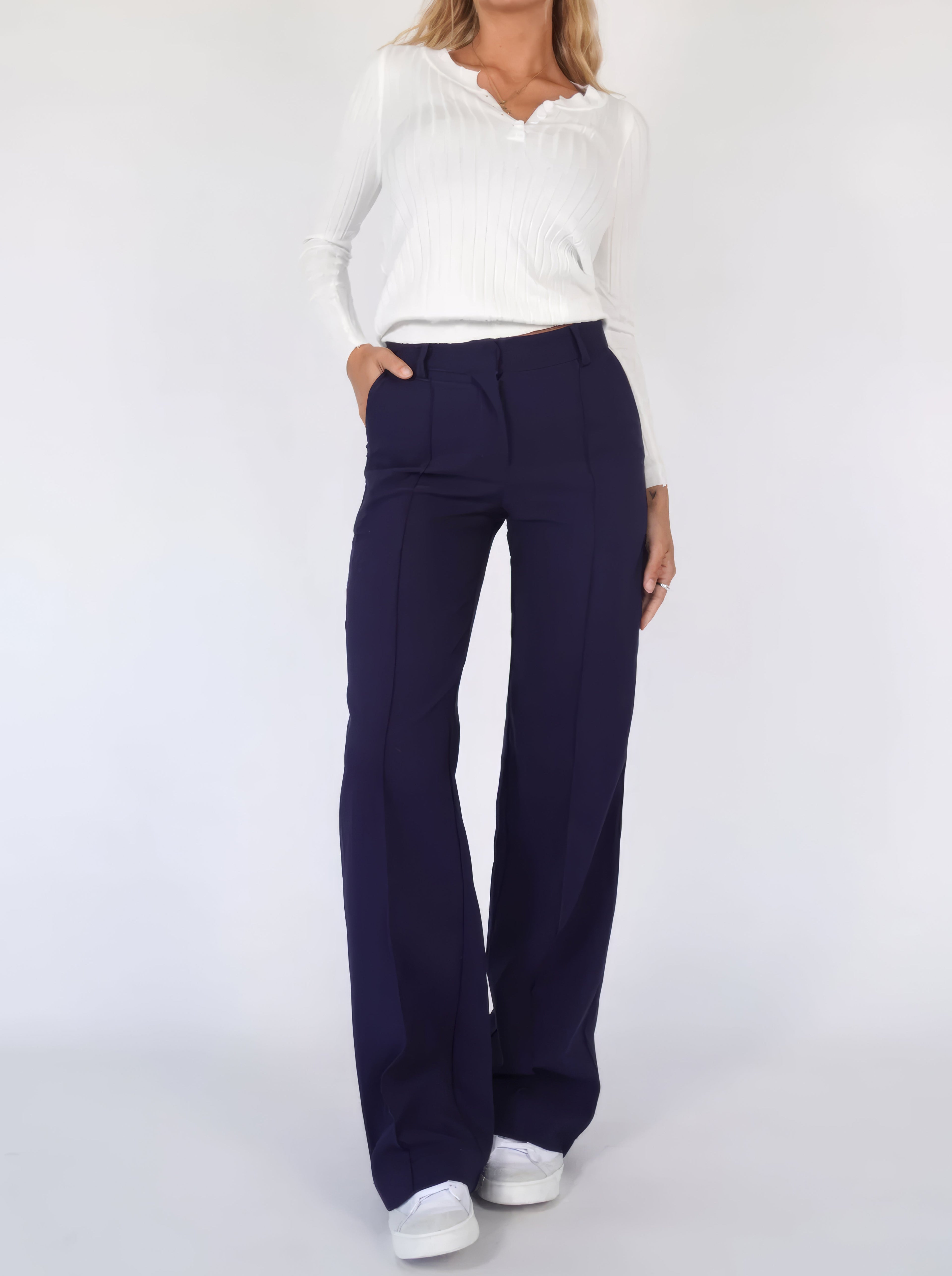 Dark blue trousers paired with a white blouse.