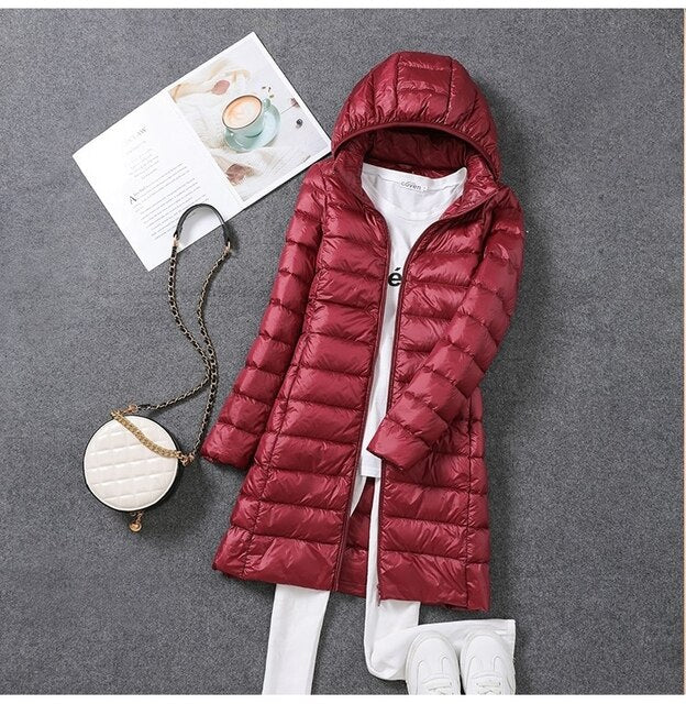 Wine-red hooded puffer coat laid out with clothing.