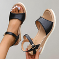 Black wedge sandals showing broad toe straps and beige footbeds.