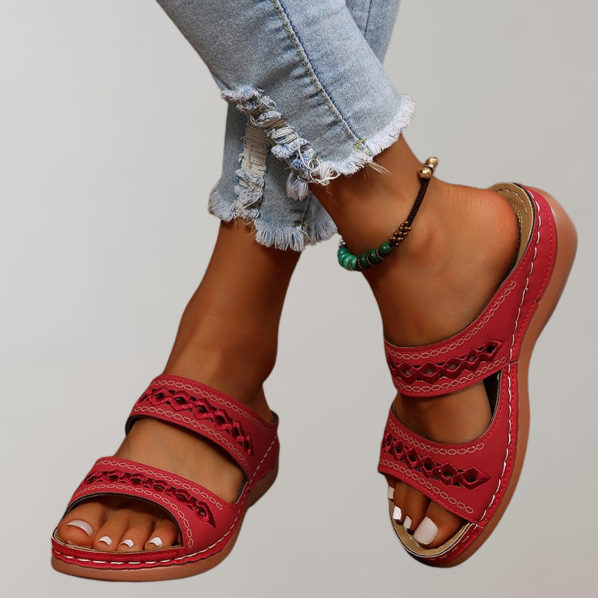 Red two-strap slide sandals with diamond cut-outs and edge stitching.