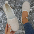 Beige canvas espadrilles with rounded toes and a heel pull tab.