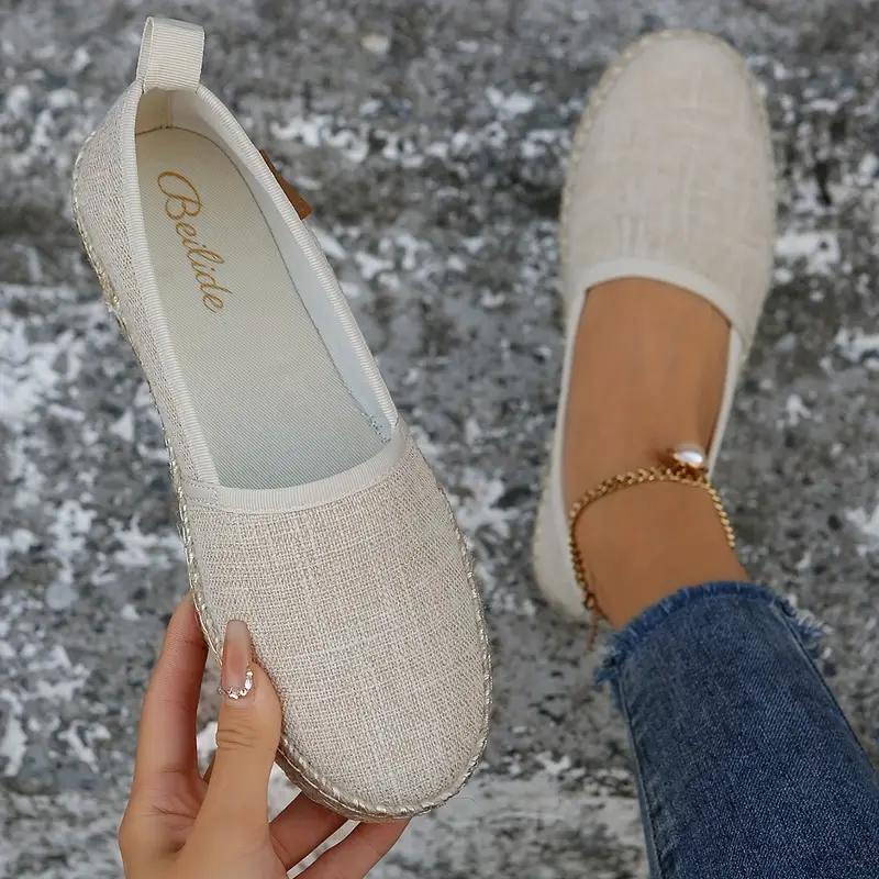 Beige canvas espadrilles with rounded toes and a heel pull tab.