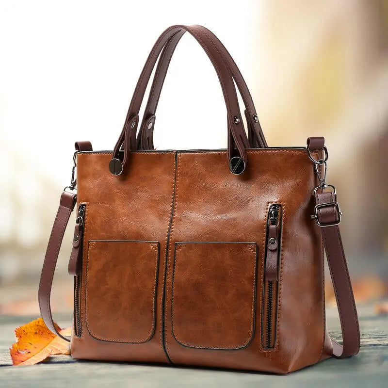 Brown handbag with twin handles, two front pockets and a long strap.
