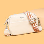 Beige bag with brown-and-white geometric strap and printed lettering.