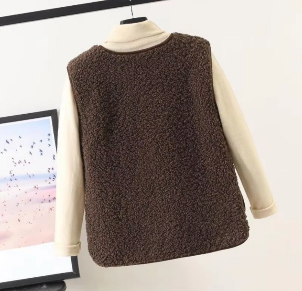 Rear view of a brown fleece gilet layered over a cream top.