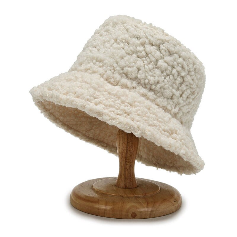 Cream curly-textured hat on a wooden display stand.