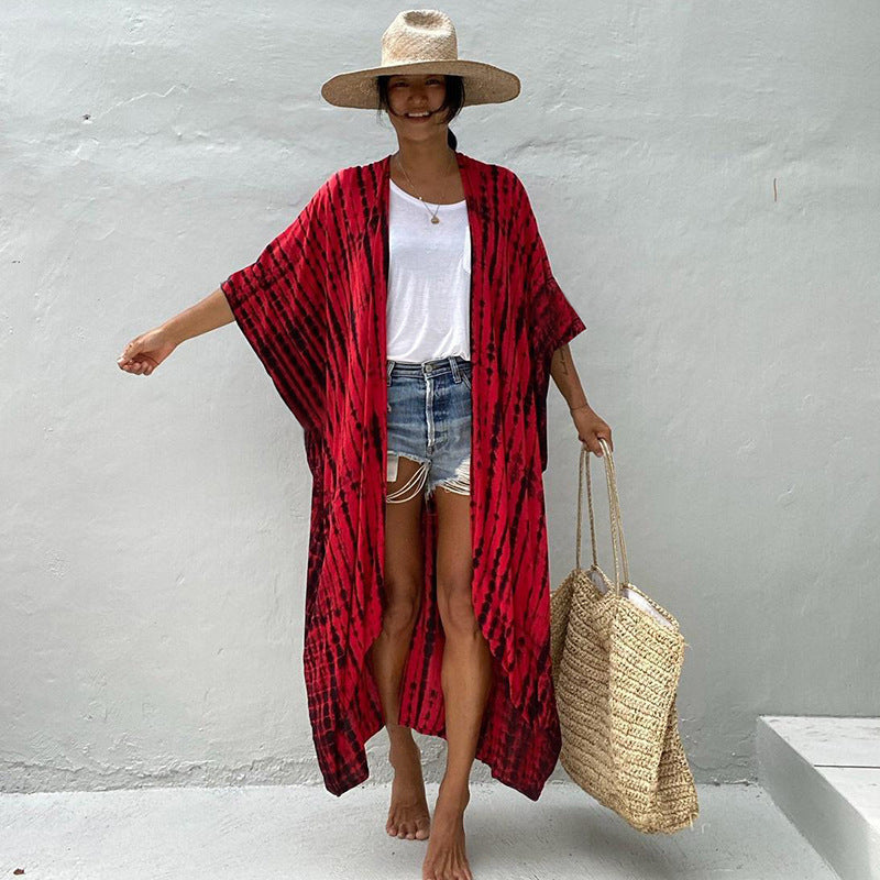 Red printed cover-up with wide sleeves worn over shorts.