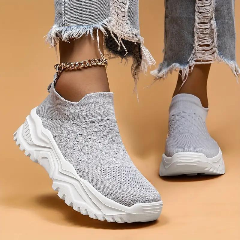 Light grey slip-on trainers with patterned uppers and white soles.