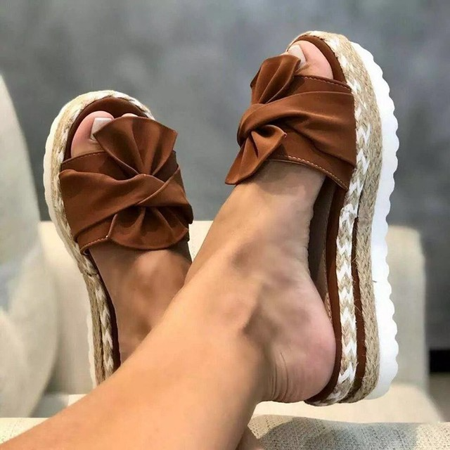 Brown bow slide sandals with textured platform edges.