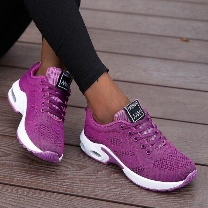 Purple trainers with white sculpted soles worn with black trousers.