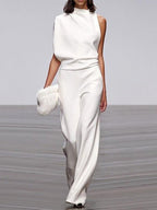 White jumpsuit with a high neckline, waist folds and wide legs.