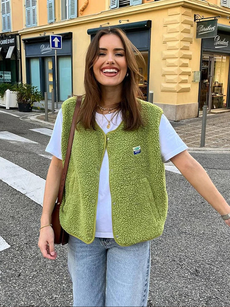 Green sleeveless textured gilet with rounded edges and front pockets.