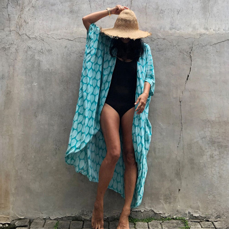 Aqua leaf-print cover-up over a black swimsuit.