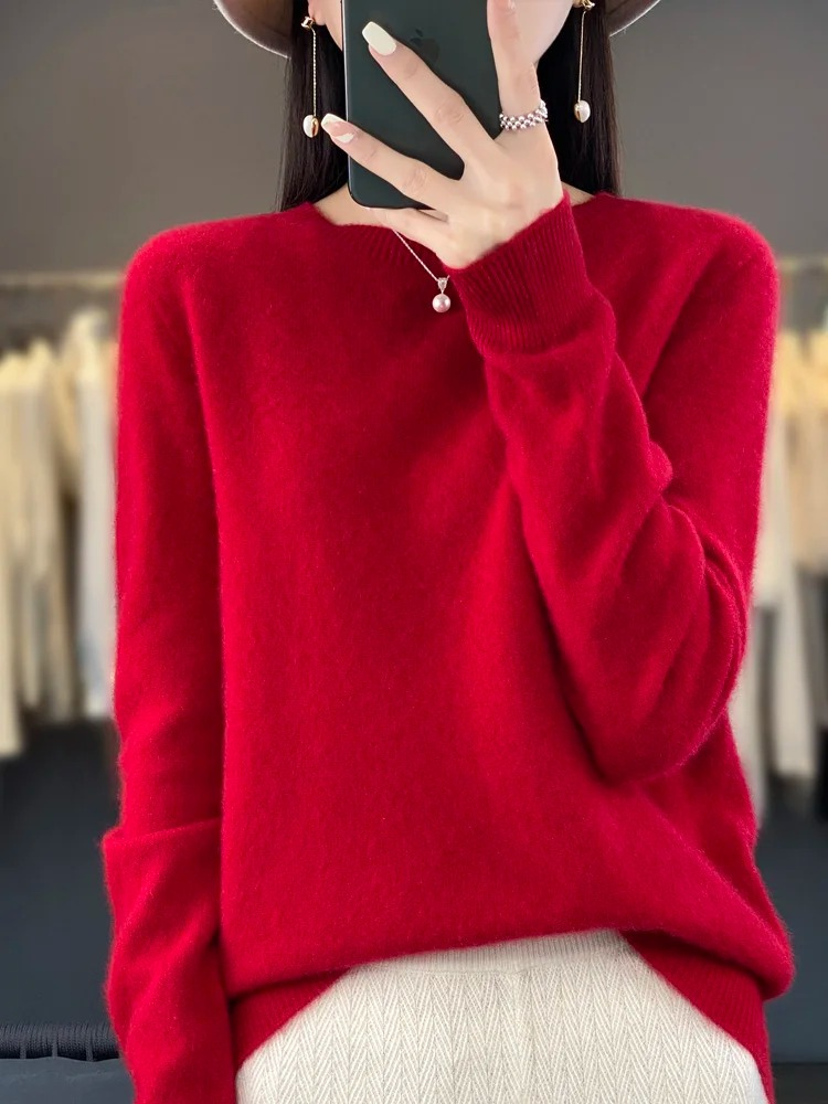 Red crew-neck jumper worn with pale trousers.