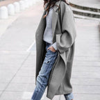 Grey oversized coat layered over a grey jumper and distressed jeans.