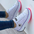 White lace-up trainers with purple sole edging and bright pink tread.