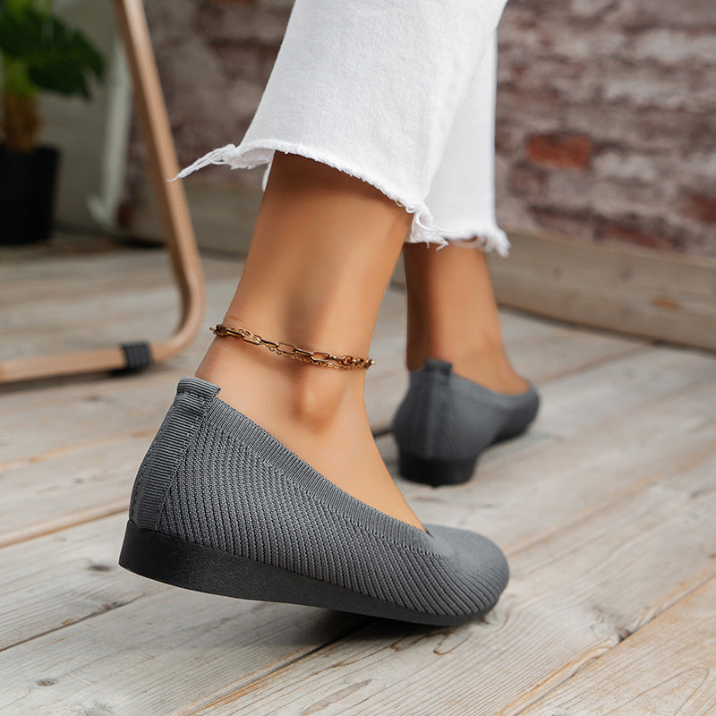 Rear view of grey flats with small heel tabs and low wedge soles.