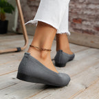 Rear view of grey flats with small heel tabs and low wedge soles.