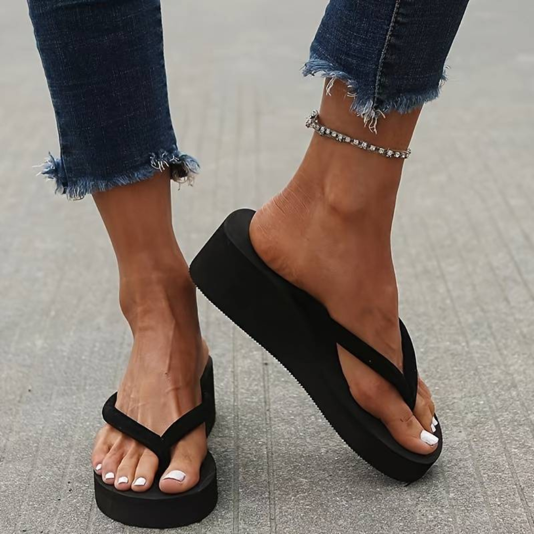 Black wedge flip-flops showing slim V-shaped toe-post straps and open heels.