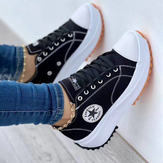 Black trainers with white piping and circular star patches.