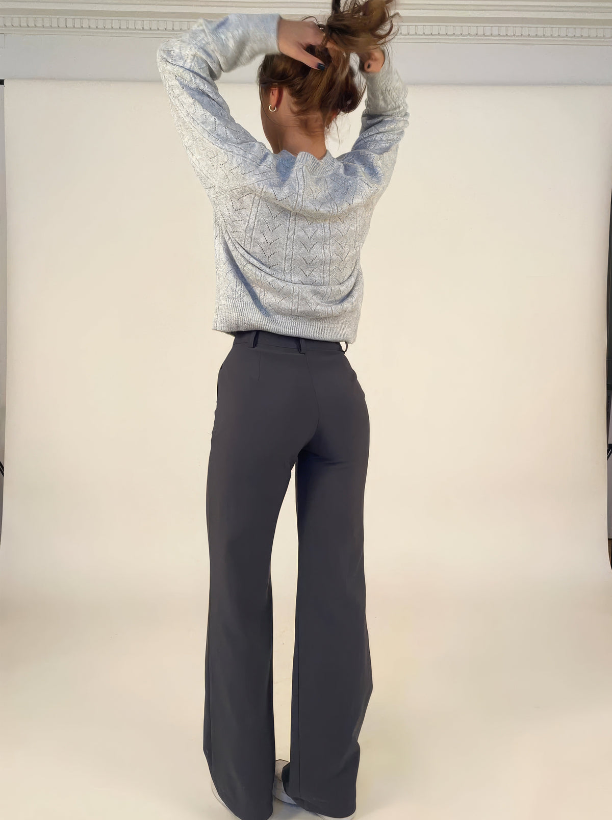 Rear view of grey wide-leg trousers worn with a cropped jumper.