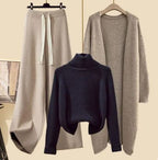 Dark navy jumper displayed beside beige drawstring trousers and a long beige jacket.