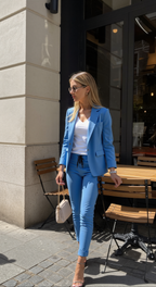 Woman wearing a blue blazer and matching drawstring trousers outside a cafe.