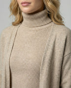Close view of a beige ribbed roll neck beneath an open knit jacket.