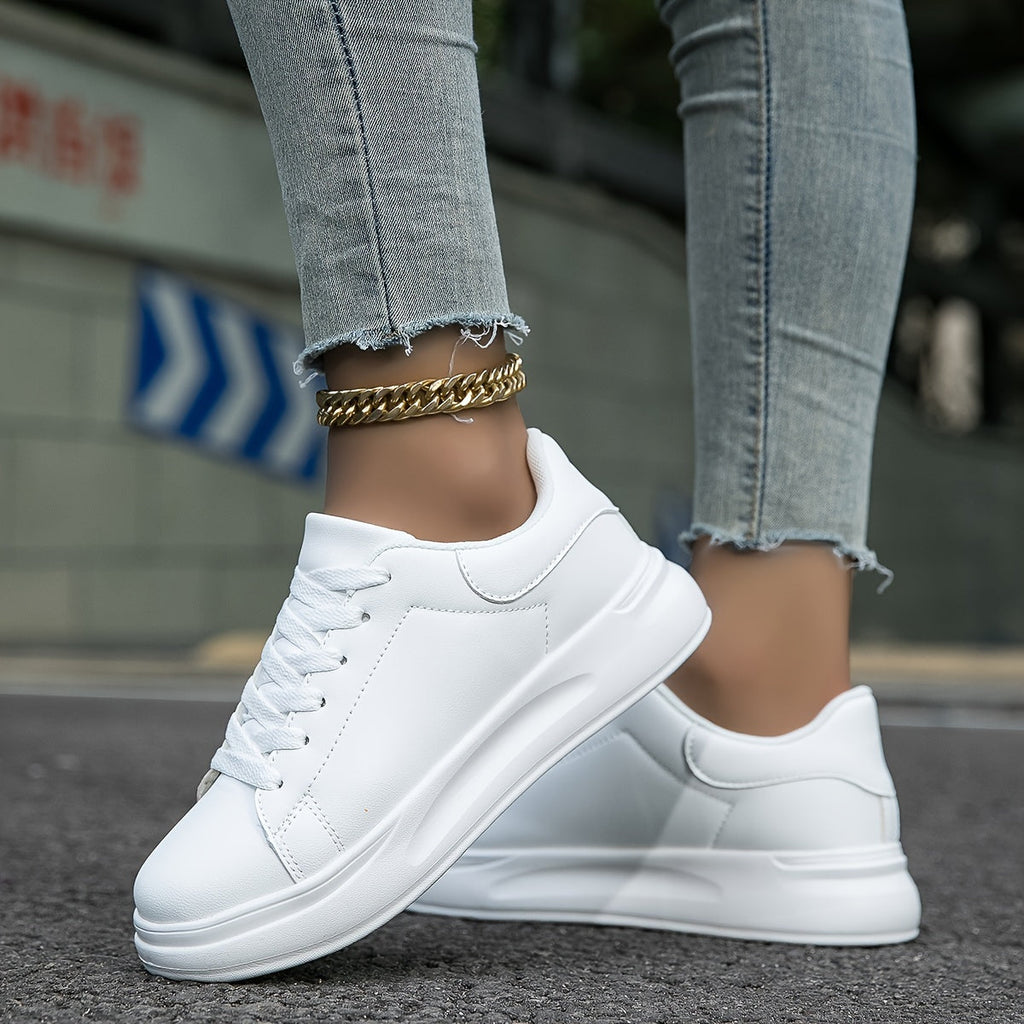 All-white lace-up trainers shown from the side, with stitched panels and thick soles.