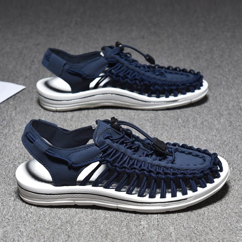 Dark blue cord sandals with white soles on a dark surface.