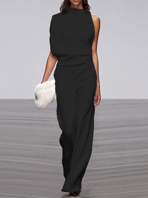 Black wide-leg jumpsuit with a draped upper section, worn with a white clutch.