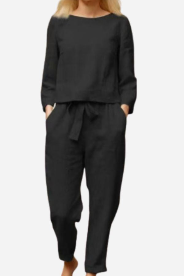 Black long-sleeve top and matching trousers with hands in the side pockets.
