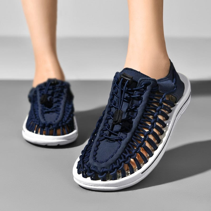 Dark blue cord sandals with toggle laces and white soles, worn from the front.