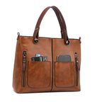 Brown handbag with a phone and cards in its front pockets.