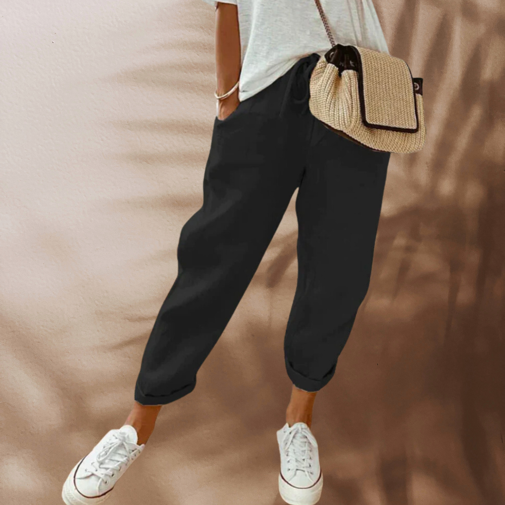 Black tapered trousers worn with white trainers.