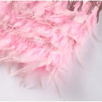 Close-up of layered pale pink feathers along the dress hem.