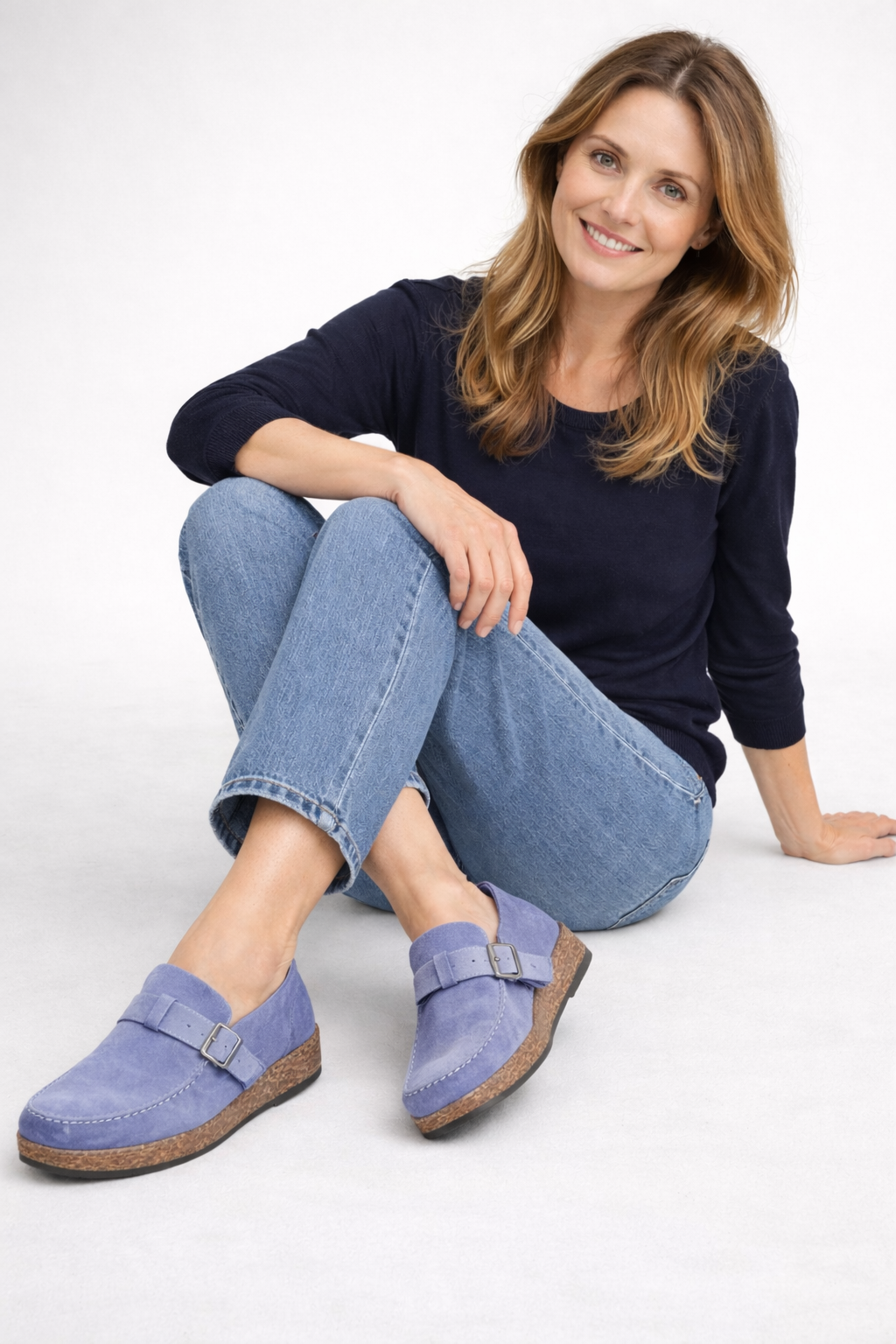 Purple-blue clogs with buckle straps worn with jeans.