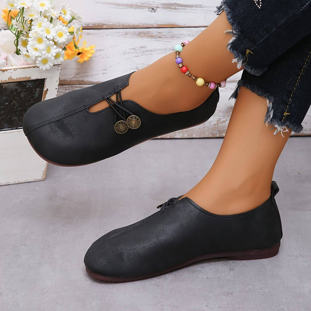 Black slip-on shoes with rounded toes and decorative lacing.