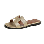 Gold cut-out slide sandal with a black sole and visible edge stitching.