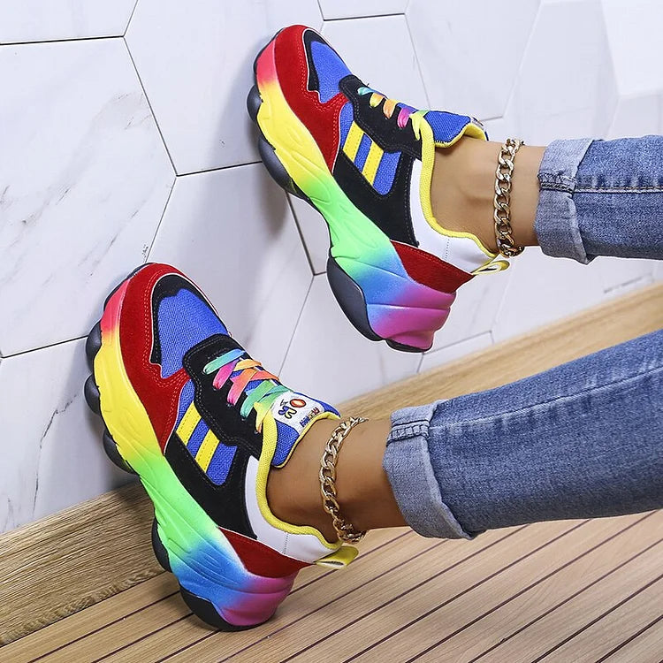 Blue and red lace-up sneakers shown in side view with rainbow soles and side stripes.