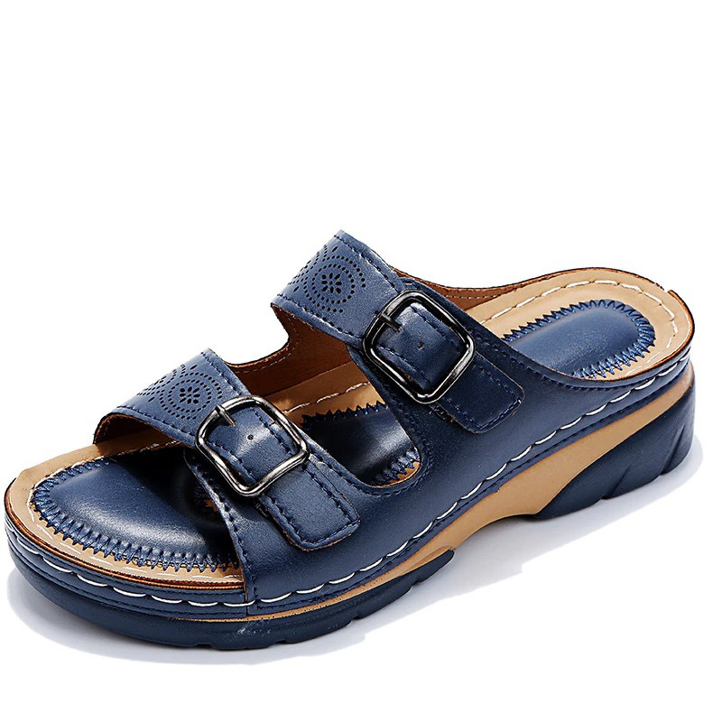 Dark blue slide sandal with metal buckles and tan detailing around the footbed.