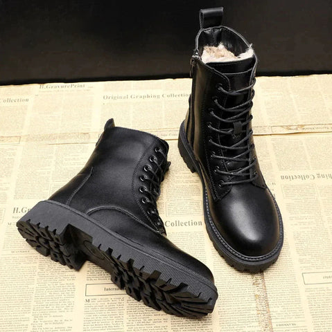 Black boots with one laid on its side to show the deep outsole tread and the other upright.