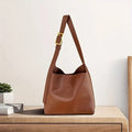 Brown shoulder bag with a wide strap and gold-coloured buckle.