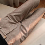 Brown-toned trousers showing a front pleat and buttoned waistband.