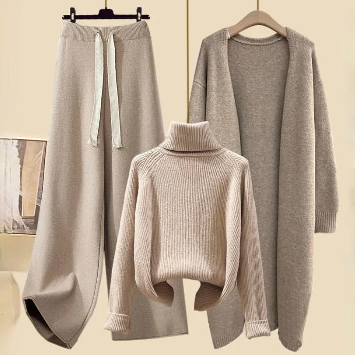 Beige jumper, drawstring trousers and matching long jacket arranged on hangers.