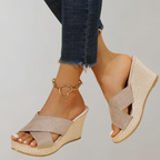 Pale beige crossed-strap wedge sandals worn with jeans.