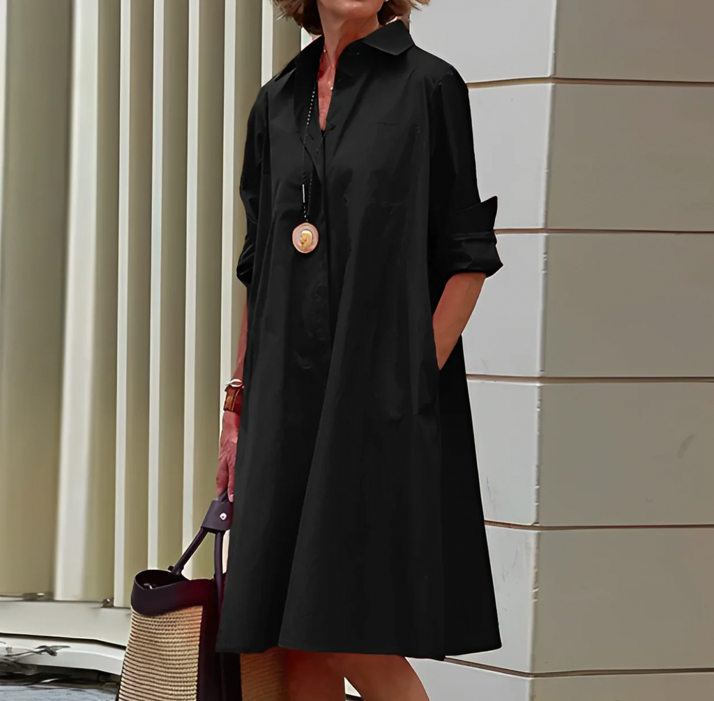 Black collared dress worn with one hand in a side pocket.