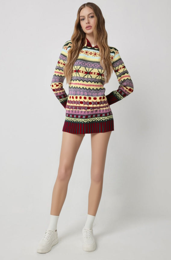 Model wearing a long multicoloured patterned sweater with dark cuffs and hem.