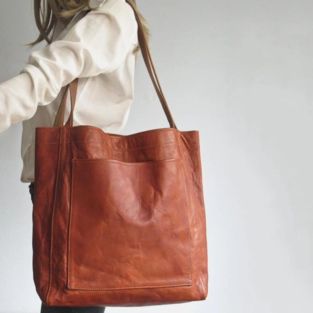 Brown tote bag with long shoulder handles and a large front patch pocket.