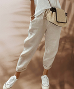 Beige relaxed trousers with a drawstring waist and rolled hems.